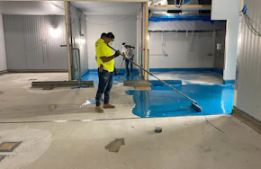 Epoxy floor coating being spread How Epoxy Floor Systems Help Protect You and Your Staff