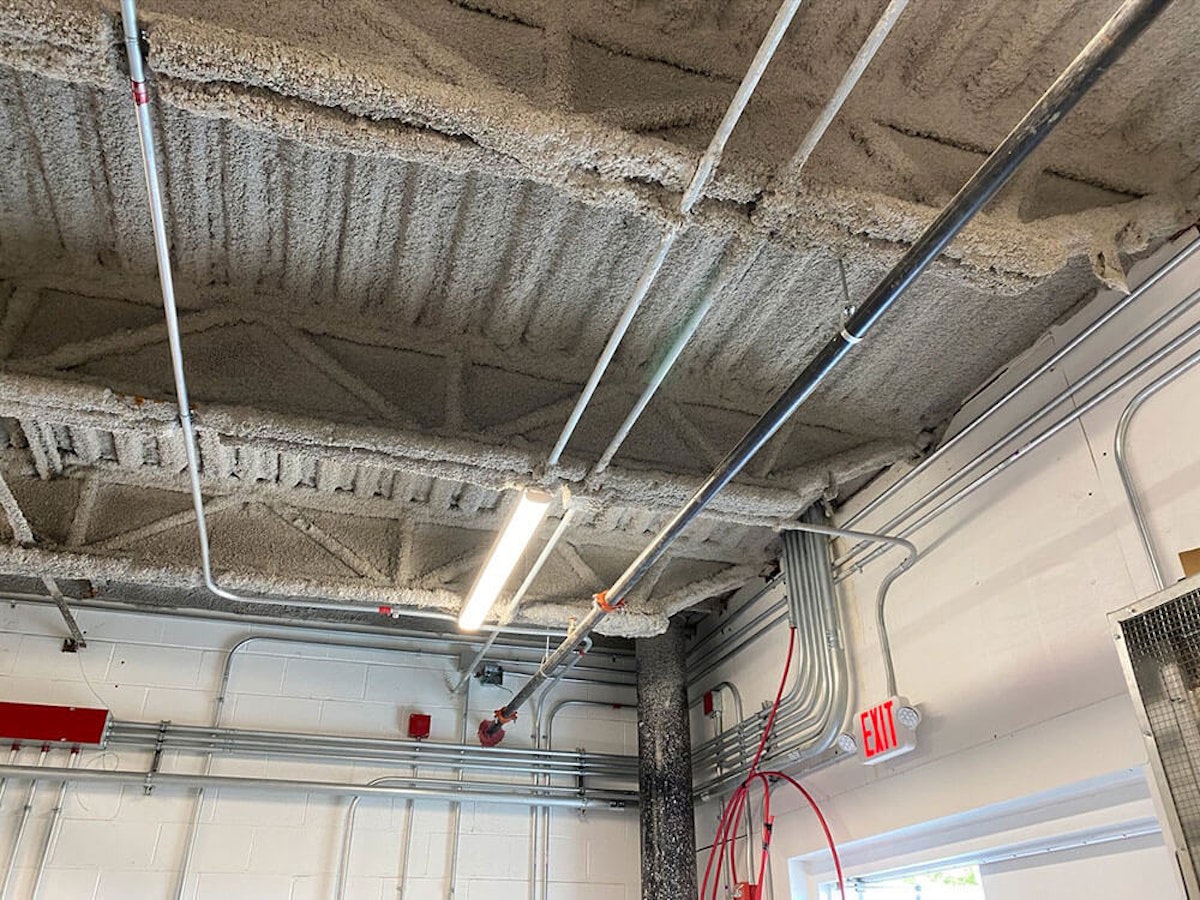 Warehouse ceiling that has been fireproofed How Warehouse Fireproofing Saves Your Commercial Business from Damage, Injury, and Financial Loss